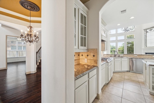 27 Tioga Pl, The Woodlands, TX 77375 - kitchen with stainless steel appliances, a chandelier, light stone counters, arched walkways, and recessed lighting