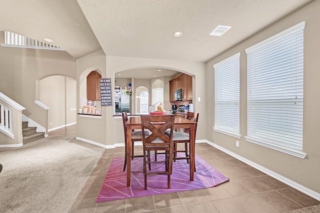 2606 Howlite Ln, Rosharon, TX 77583 - carpeted dining space featuring tile patterned floors, stairway, a textured ceiling, baseboards, and visible vents