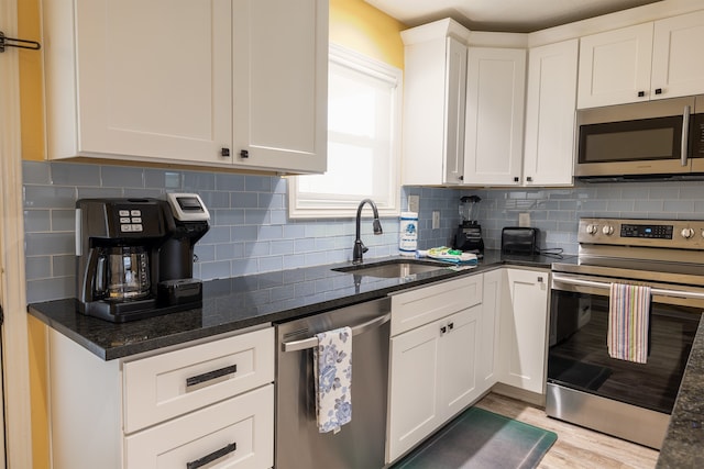 4206 Seabird Dr, Galveston, TX 77554 - kitchen featuring appliances with stainless steel finishes, white cabinets, light wood finished floors, dark stone counters, and decorative backsplash