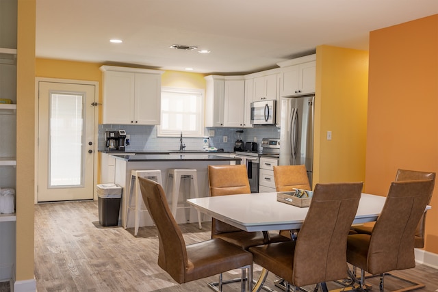 4206 Seabird Dr, Galveston, TX 77554 - kitchen featuring appliances with stainless steel finishes, light wood-style floors, dark countertops, white cabinets, and recessed lighting
