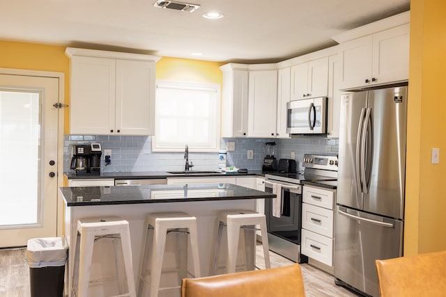 4206 Seabird Dr, Galveston, TX 77554 - kitchen featuring stainless steel appliances, a kitchen bar, tasteful backsplash, a kitchen island, and light wood finished floors