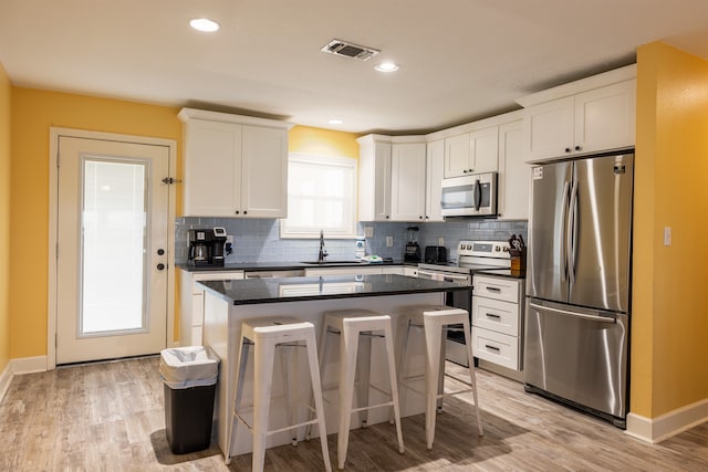 4206 Seabird Dr, Galveston, TX 77554 - kitchen with appliances with stainless steel finishes, dark countertops, a kitchen island, a breakfast bar, and recessed lighting