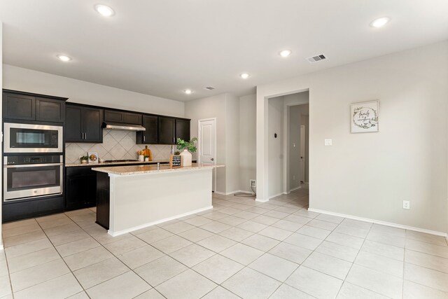 5014 Aspen Orchard Dr, Houston, TX 77066 - kitchen featuring stainless steel appliances, backsplash, light tile patterned flooring, a center island with sink, and under cabinet range hood