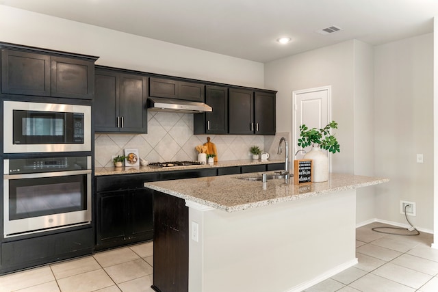 5014 Aspen Orchard Dr, Houston, TX 77066 - kitchen featuring stainless steel appliances, a sink, under cabinet range hood, light tile patterned floors, and light stone countertops