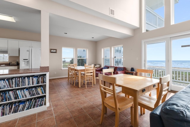 22915 Gulf Dr, Galveston, TX 77554 - dining room featuring a water view, baseboards, dark tile patterned floors, and visible vents