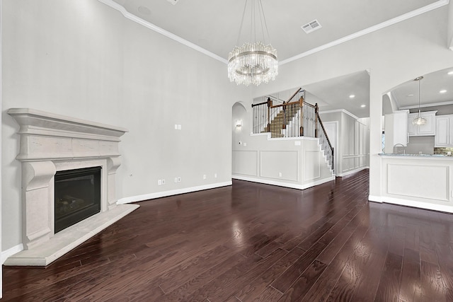 3411 Heather Garden Trl, Richmond, TX 77406 - unfurnished living room featuring arched walkways, crown molding, wood finished floors, a premium fireplace, and stairway