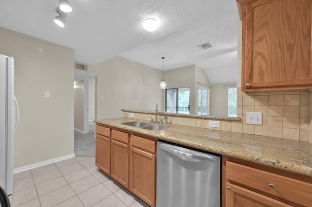 kitchen with decorative backsplash, stainless steel dishwasher, a sink, light stone counters, and freestanding refrigerator