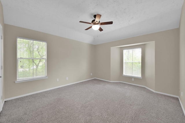 empty room with a textured ceiling, lofted ceiling, baseboards, ceiling fan, and carpet