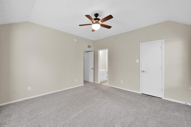 interior space with baseboards, ceiling fan, vaulted ceiling, and light carpet