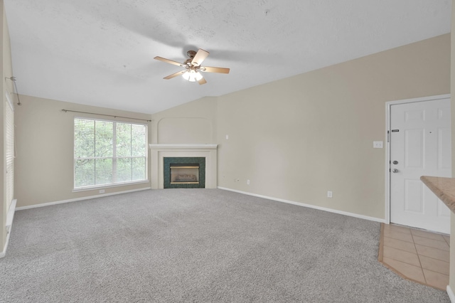 unfurnished living room with vaulted ceiling, a ceiling fan, a fireplace, baseboards, and carpet