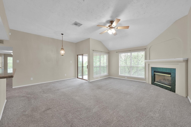 unfurnished living room featuring vaulted ceiling, carpet floors, a tile fireplace, visible vents, and ceiling fan
