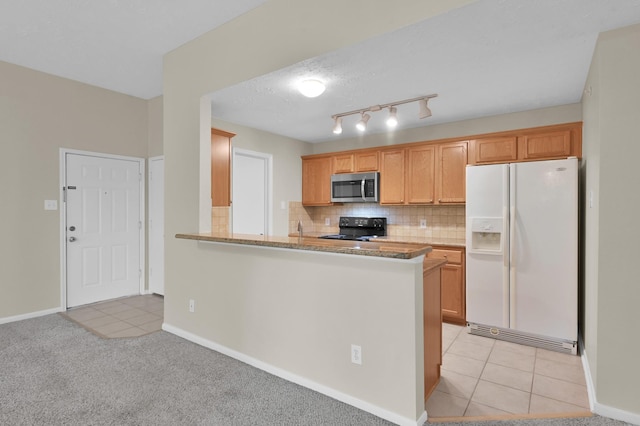 kitchen featuring light tile patterned flooring, backsplash, black electric range oven, white fridge with ice dispenser, and stainless steel microwave