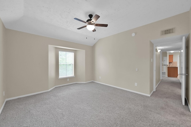 spare room with vaulted ceiling, a ceiling fan, baseboards, visible vents, and carpet