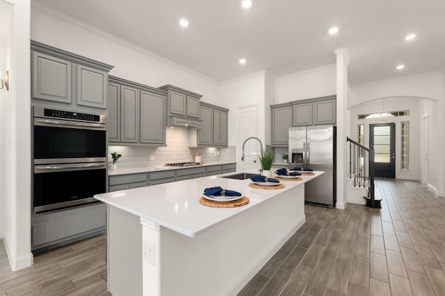 6518 Fairway Glen Ln, Katy, TX 77493 - kitchen featuring gray cabinets, decorative backsplash, appliances with stainless steel finishes, a sink, and a center island with sink