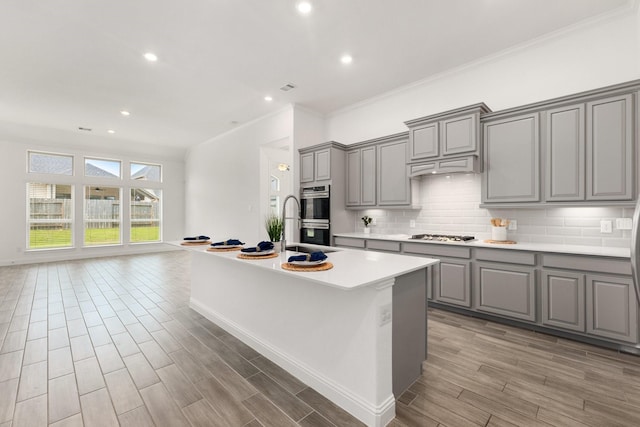 6518 Fairway Glen Ln, Katy, TX 77493 - kitchen featuring a kitchen island with sink, stainless steel appliances, decorative backsplash, and gray cabinets
