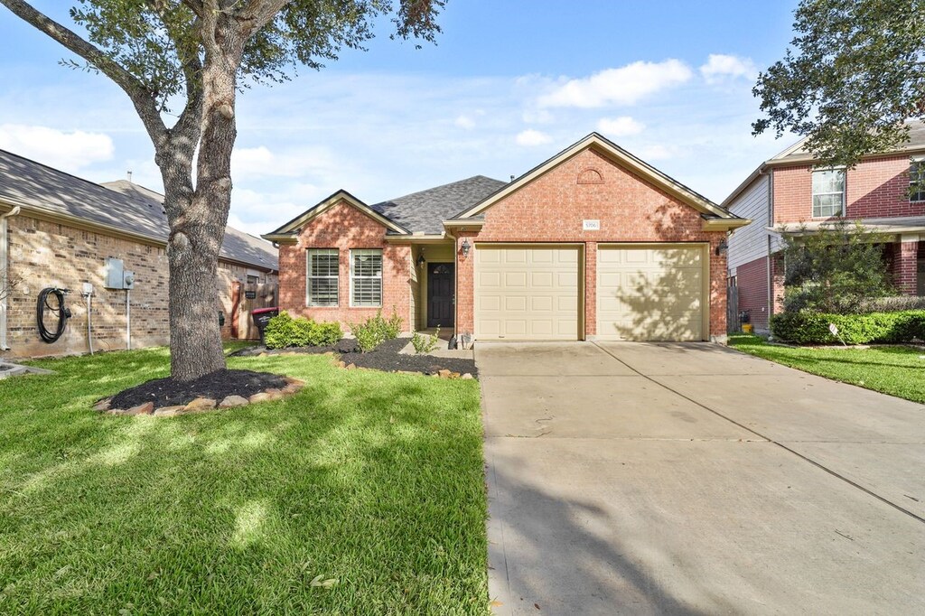 ranch-style home with a garage, concrete driveway, a front yard, brick siding, and a shingled roof