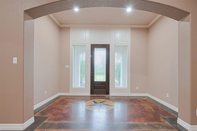 entryway with ornamental molding, baseboards, recessed lighting, and arched walkways