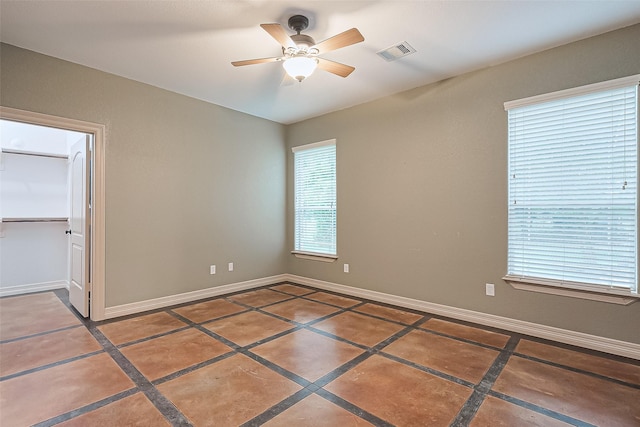 unfurnished bedroom featuring ceiling fan, baseboards, a spacious closet, and visible vents