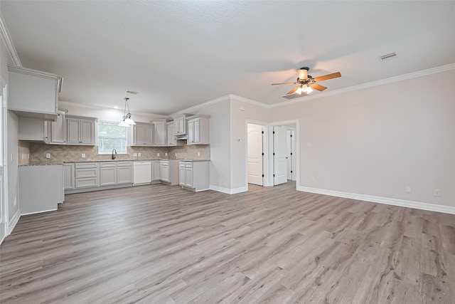 kitchen with a sink, open floor plan, tasteful backsplash, and ornamental molding