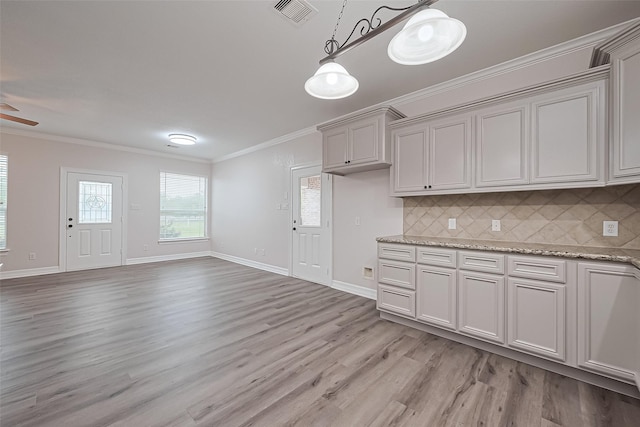 kitchen with tasteful backsplash, visible vents, hanging light fixtures, ornamental molding, and light wood-style floors