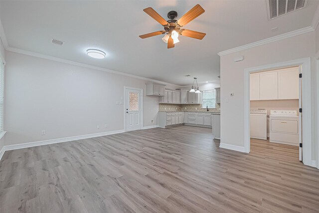 unfurnished living room featuring visible vents, washer and dryer, ornamental molding, a ceiling fan, and light wood-style floors