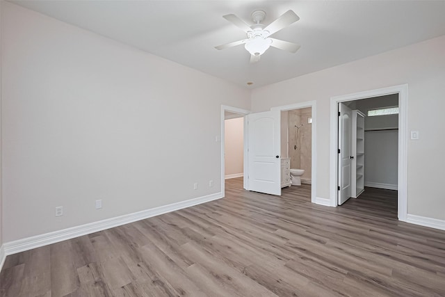 unfurnished bedroom with baseboards, a walk in closet, and wood finished floors