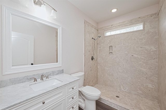 full bath with toilet, vanity, and a tile shower