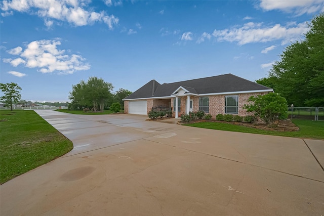 ranch-style home featuring a front yard, an attached garage, fence, concrete driveway, and brick siding