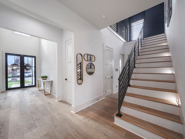 stairway featuring wood finished floors, a high ceiling, and baseboards