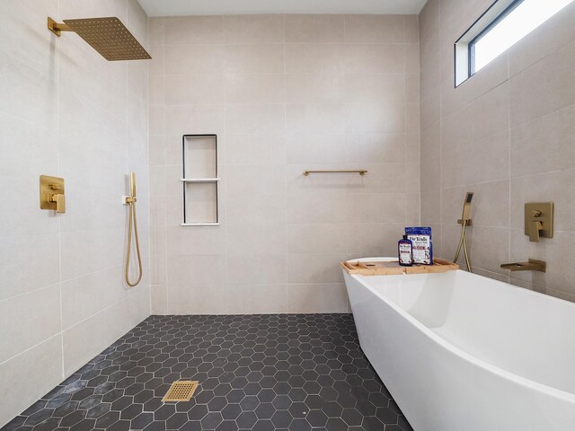 bathroom with a tile shower, a freestanding tub, and tile walls