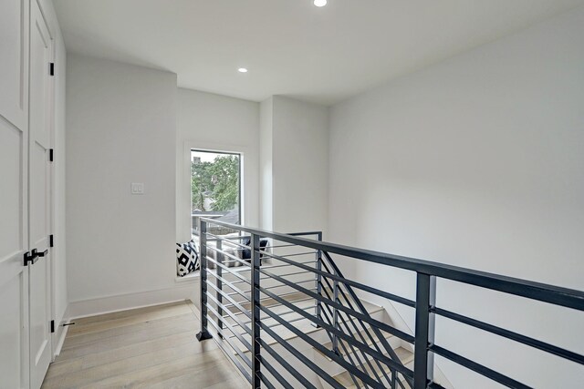 corridor featuring an upstairs landing, recessed lighting, light wood-style flooring, and baseboards
