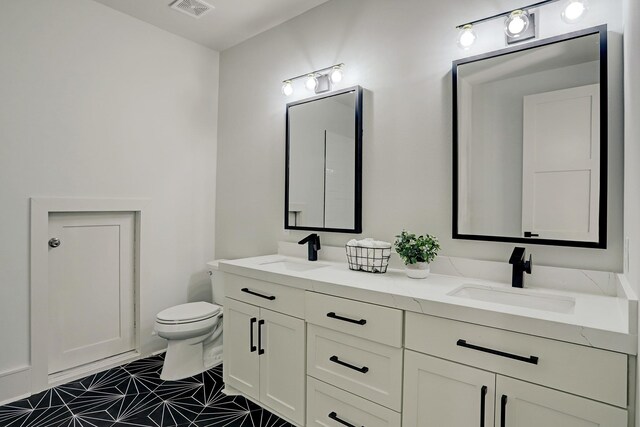 bathroom with toilet, double vanity, and tile patterned floors
