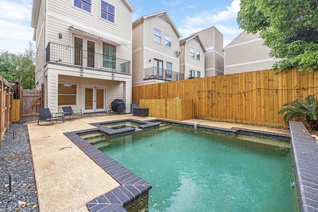 back of house featuring a balcony, a patio, french doors, and a fenced backyard