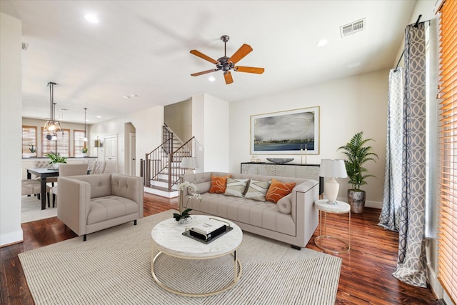 living area with ceiling fan, visible vents, wood finished floors, and stairway