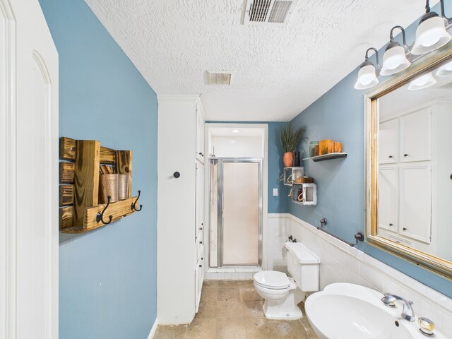 1310 Golden Bear Ln, Kingwood, TX 77339 - full bathroom featuring a shower stall, a textured ceiling, toilet, a sink, and a wainscoted wall