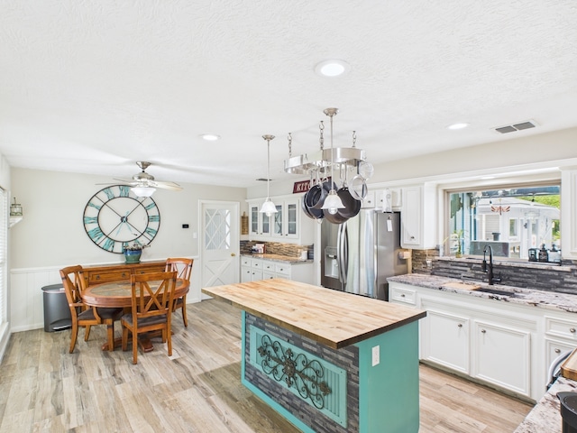 1310 Golden Bear Ln, Kingwood, TX 77339 - kitchen featuring stainless steel refrigerator with ice dispenser, wooden counters, white cabinetry, light wood-style floors, and wainscoting