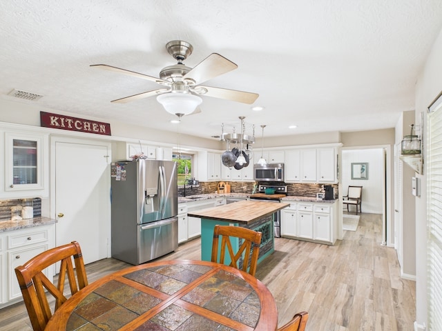 1310 Golden Bear Ln, Kingwood, TX 77339 - kitchen featuring appliances with stainless steel finishes, butcher block counters, light wood finished floors, tasteful backsplash, and recessed lighting