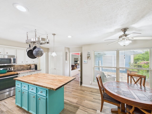 1310 Golden Bear Ln, Kingwood, TX 77339 - kitchen with appliances with stainless steel finishes, butcher block counters, blue cabinetry, a ceiling fan, and decorative backsplash