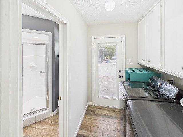 1310 Golden Bear Ln, Kingwood, TX 77339 - laundry room featuring cabinet space, separate washer and dryer, a textured ceiling, light wood finished floors, and baseboards