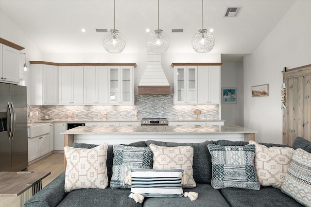 986 Bolivar Dunes Blvd, Gilchrist, TX 77617 - kitchen with appliances with stainless steel finishes, decorative backsplash, custom range hood, light countertops, and lofted ceiling