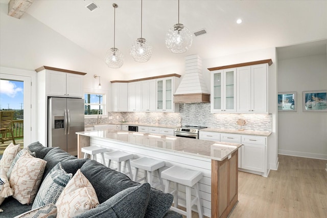 986 Bolivar Dunes Blvd, Gilchrist, TX 77617 - kitchen featuring stainless steel appliances, premium range hood, decorative backsplash, a kitchen breakfast bar, and high vaulted ceiling