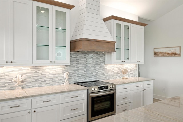 986 Bolivar Dunes Blvd, Gilchrist, TX 77617 - kitchen with stainless steel range with electric stovetop, custom exhaust hood, backsplash, and light stone countertops