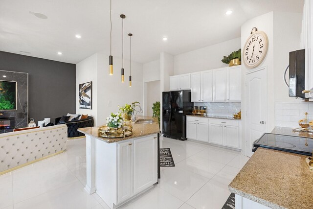 kitchen with black refrigerator with ice dispenser, white cabinets, a sink, and stainless steel microwave