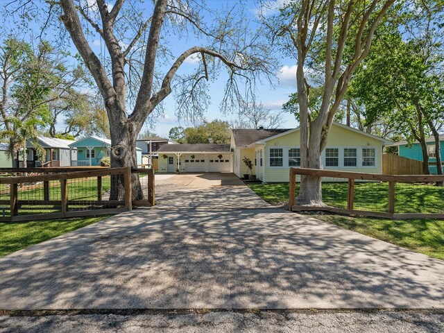 view of front facade featuring a front lawn, driveway, a fenced front yard, and an attached garage