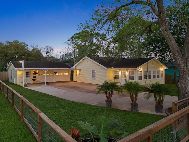 back of house at dusk featuring a patio area, concrete driveway, fence, an attached garage, and a lawn