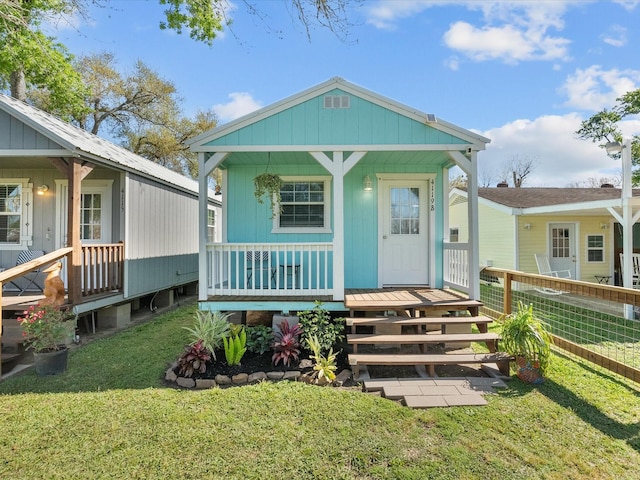 view of front of home with a front lawn, fence, and a porch