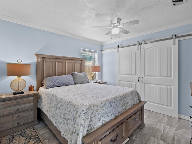 bedroom with crown molding, visible vents, a barn door, and a textured ceiling