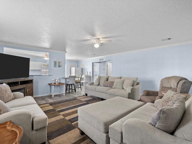 living area with ceiling fan, visible vents, and ornamental molding