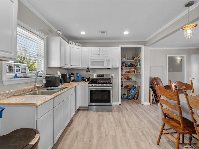 kitchen with light countertops, ornamental molding, a sink, white microwave, and stainless steel gas stove