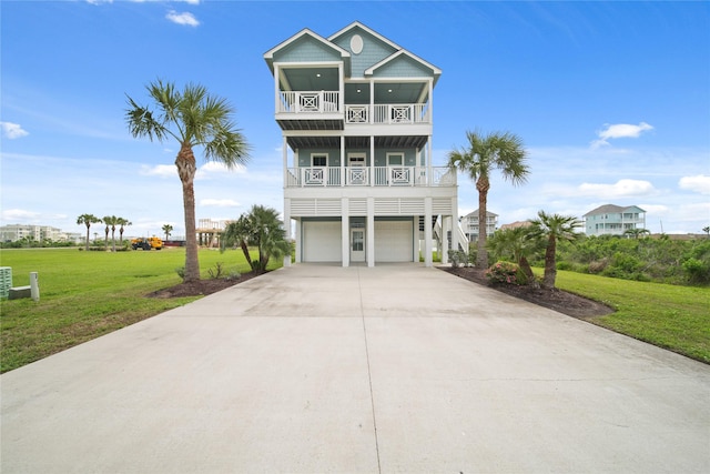 26711 Bay Water Dr, Galveston, TX 77554 - coastal home with an attached garage, a balcony, a front lawn, and driveway